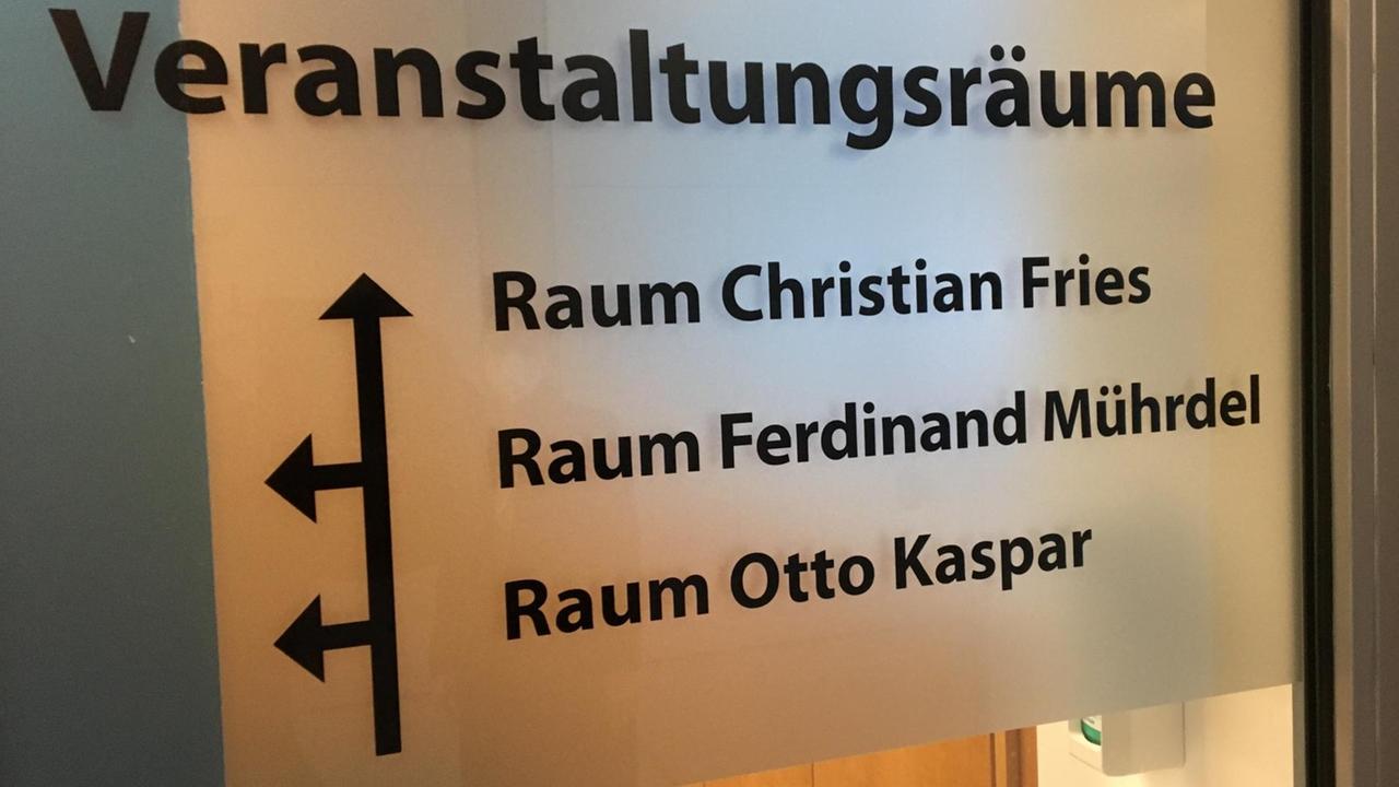 Auf einer Glastür im Polizeipräsidium Frankfurt am Main stehen die Namen der Polizisten Christian Fries, Ferdinand Mührdel und Otto Kaspar, die im Widerstand gegen den Nationalsozialismus tätig waren. 