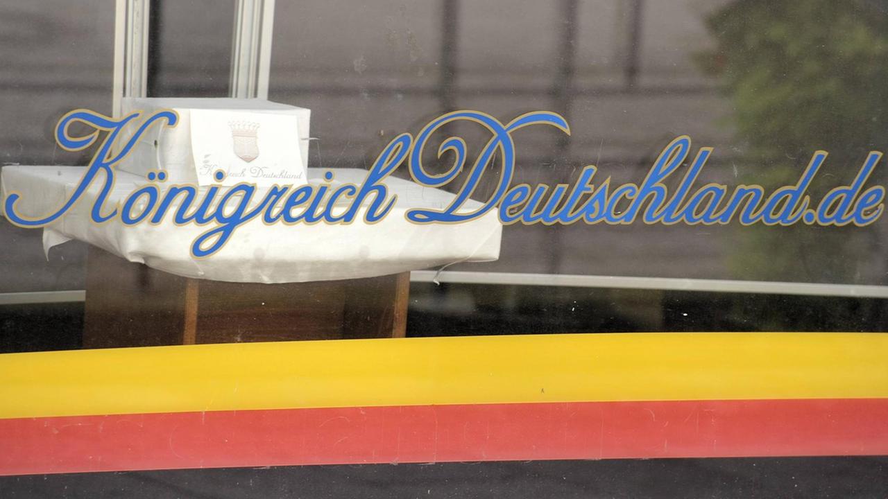 Schriftzug Königreich Deutschland.de auf der Schaufensterscheibe eines Ladengeschäftes in Lutherstadt Wittenberg; darunter die umgedrehten Farben der Deutschlandfahne. 