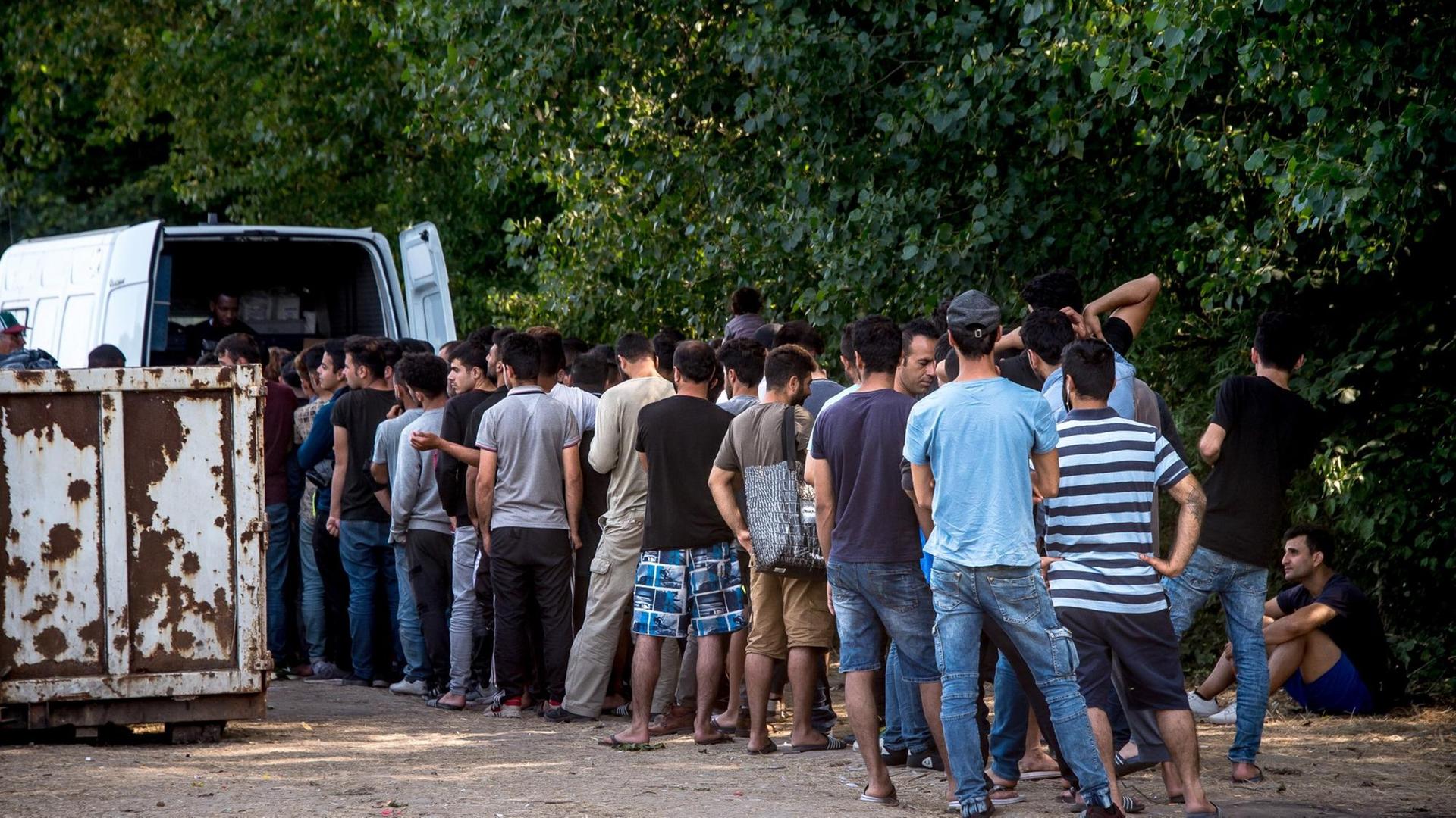 Flüchtlinge in der französischen Präfektur Grande-Synthe stehen in einer Reihe vor einem Versorgungstransporter an