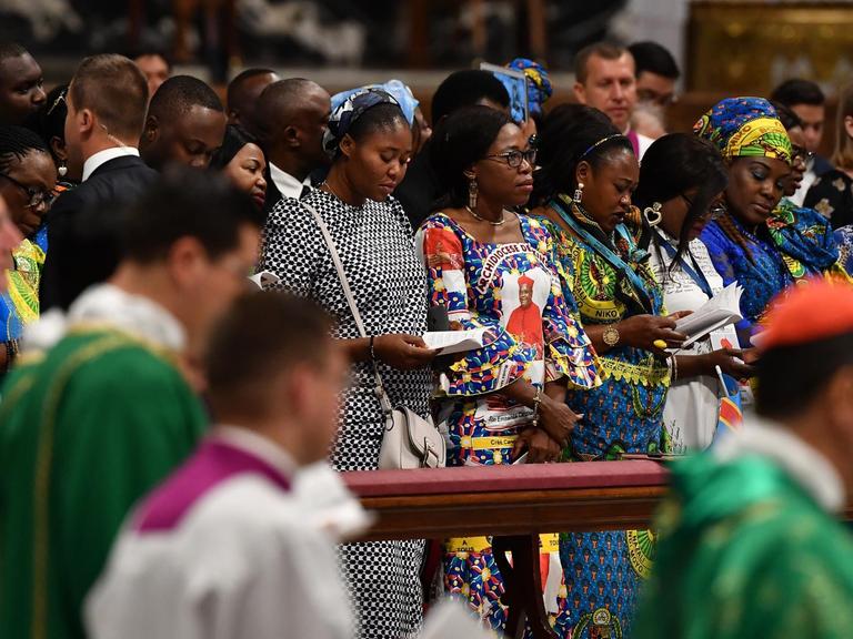Frauen aus der Amazonas-Region stehen während der Messe in den Kirchenbänken. Daneben: Geistliche und Messdiener.
