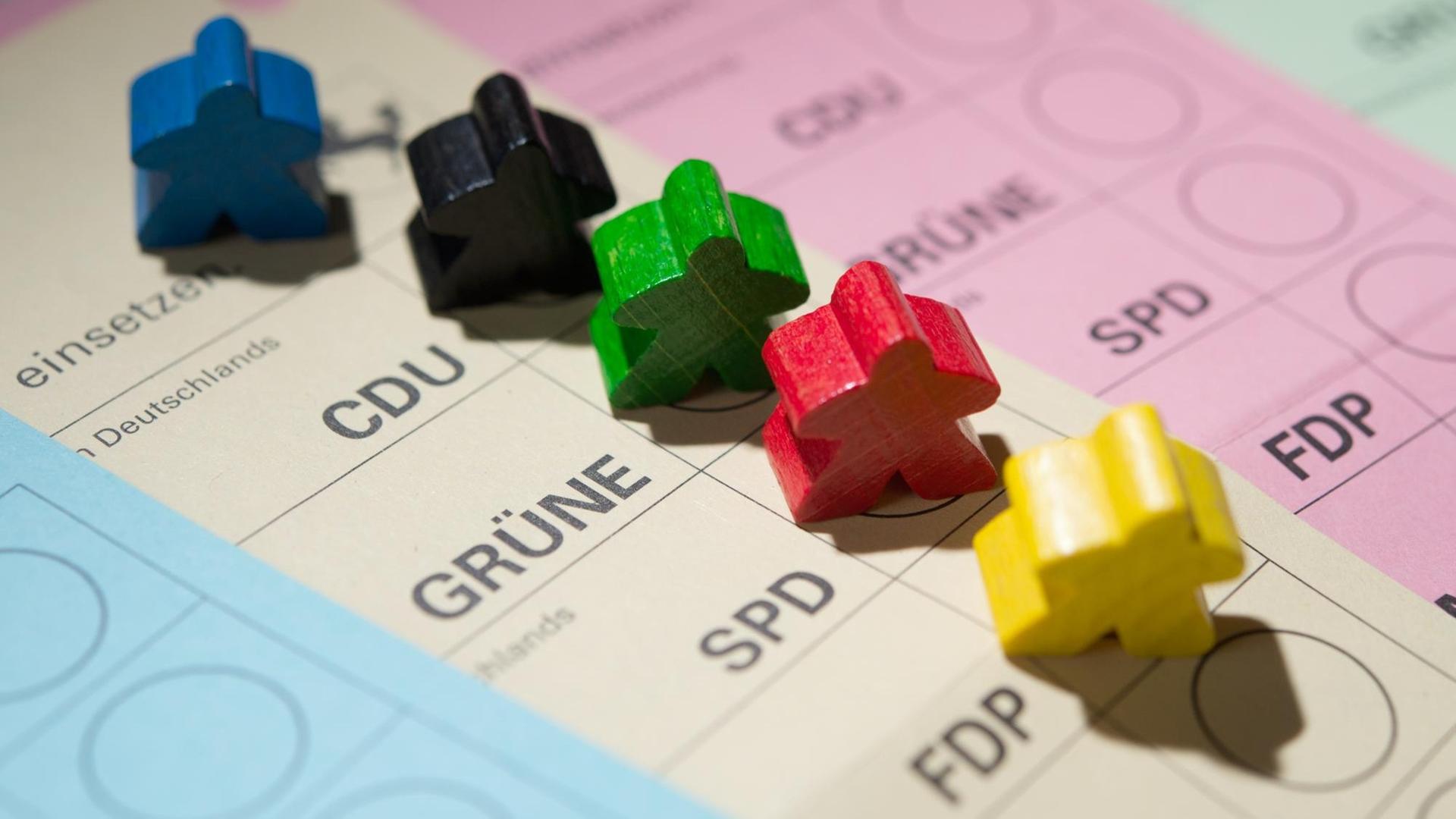 Farbige Spielfiguren stehen auf Wahlscheinen.