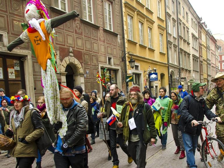 Eine Gruppe von Menschen zieht mit einer Strohpuppe durch die Altstadt von Warschau.