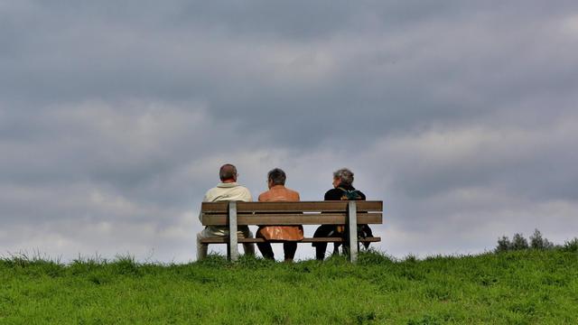 Ältere Menschen sitzen auf einer Bank.