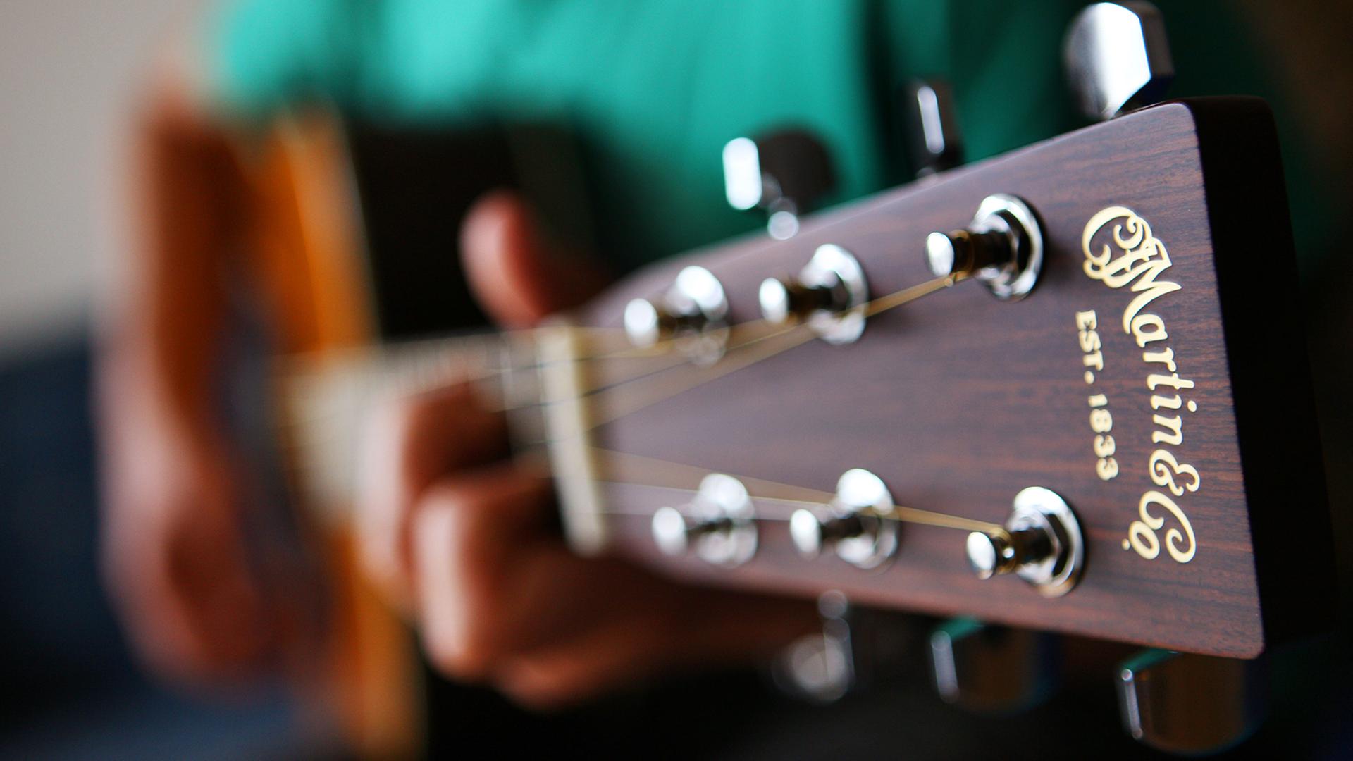 Ein Gitarrist spielt auf einer Stahlsaiten-Akustikgitarre
