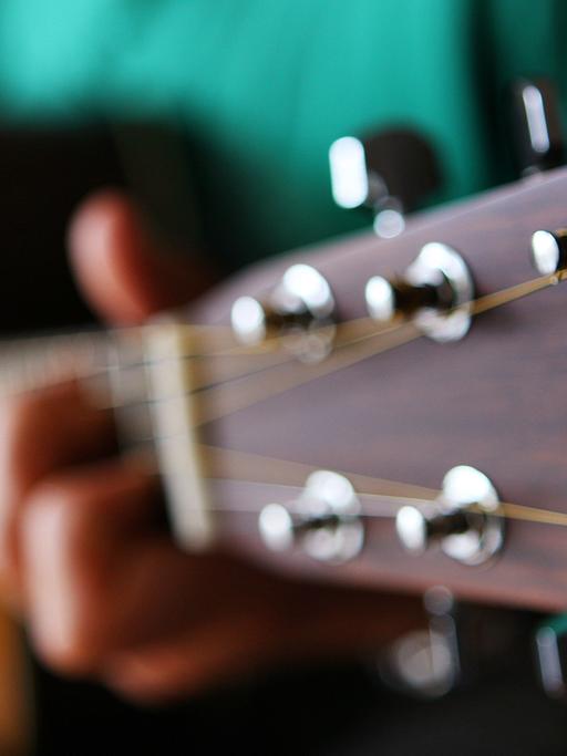 Ein Gitarrist spielt auf einer Stahlsaiten-Akustikgitarre