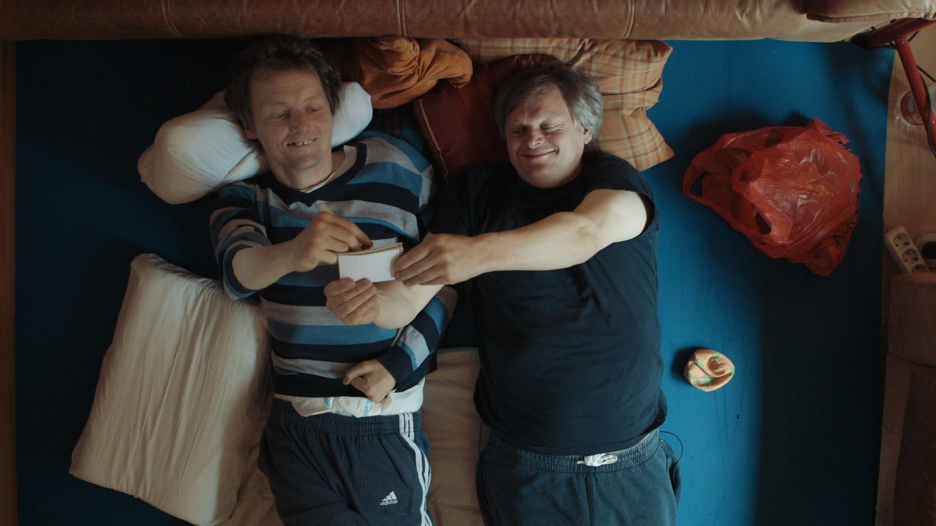 Filmszene aus Bruderliebe: Markus und Michael liegen nebeneinander vergnügt im Bett.