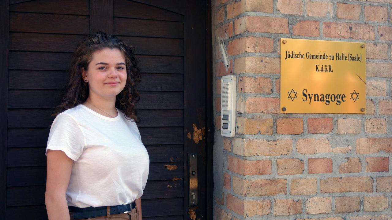 Porträt der angehenden Kunststudentin Lidia Edel vor der hölzernen Eingangstür zur Synagoge