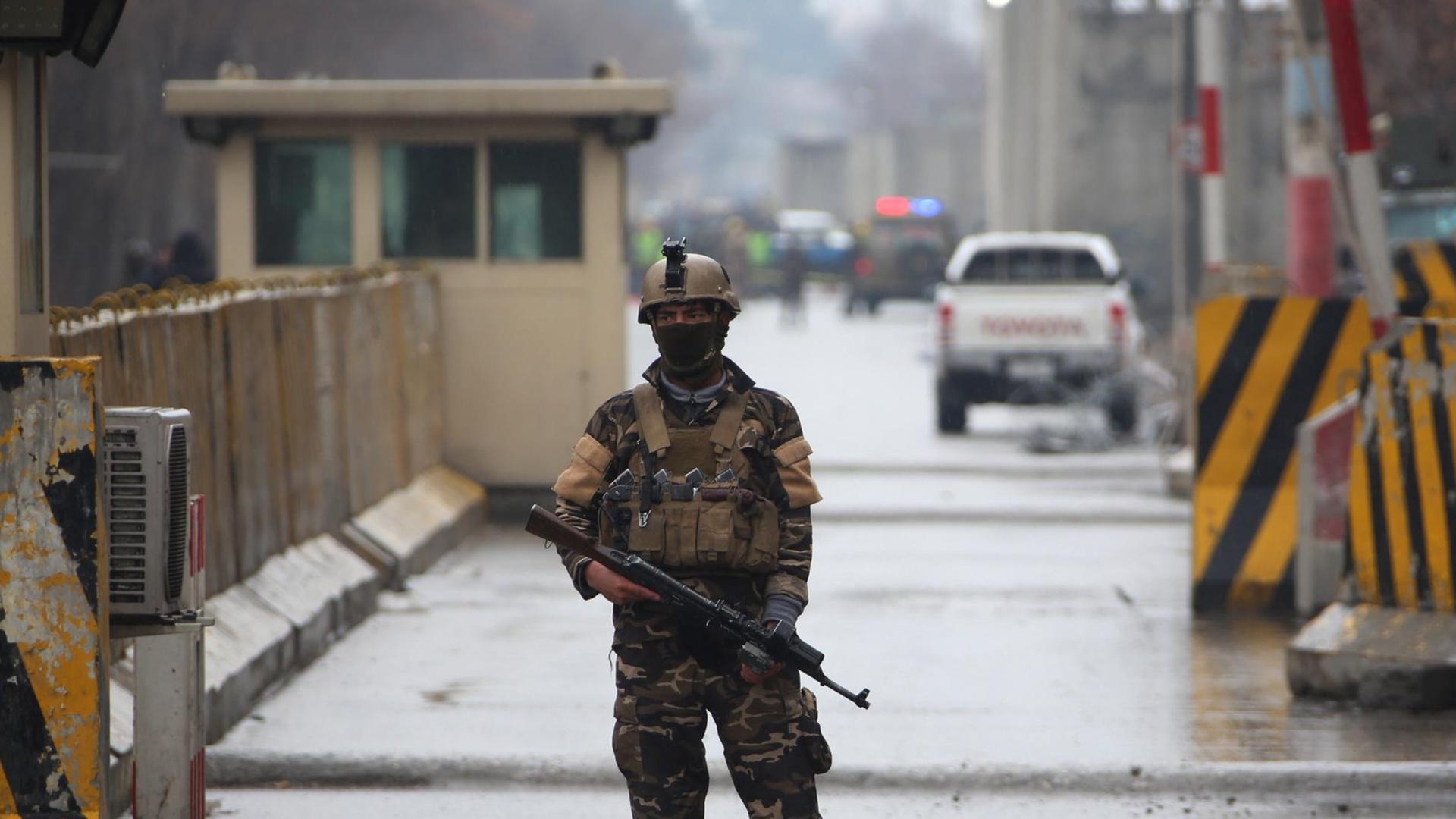 Bewaffneter Soldat auf einer Straße in Kabul, im Hintergrund gelb-schwarze Absperrungen