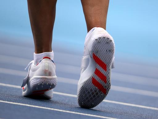 Eine Sportlerin trainiert auf einer Laufbahn. Das Bild zeigt nur ihre Füße in Laufschuhen.