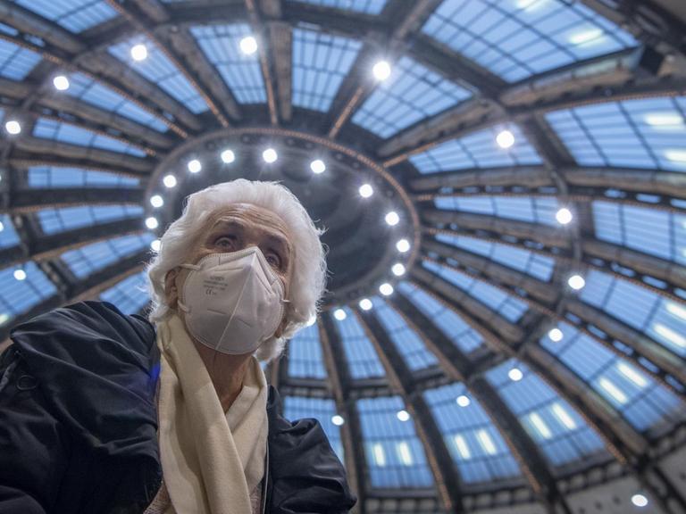 Nachdem sie ihre Impfung gegen das neuartige Coronavirus erhalten hat, sitzt die 90-jährige Odores H. unter dem Kuppeldach des Impfzentrums in der Festhalle in Frankfurt.