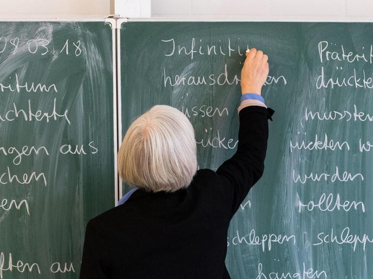 Eine Lehrerin der Oberschule an der Ronzelenstraße in Bremen steht in einem Klassenraum an einer Tafel und schreibt.