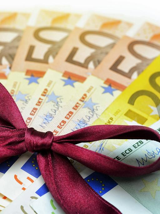 560 Euro mit Geschenkschleife - Symboldbild: Bedingungsloses grundeinkommen