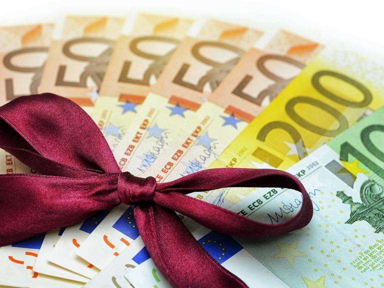 560 Euro mit Geschenkschleife - Symboldbild: Bedingungsloses grundeinkommen