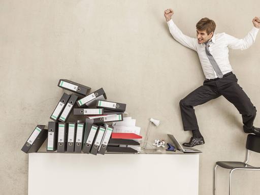 Ein Mensch springt auf seinen Bürostuhl und Tisch