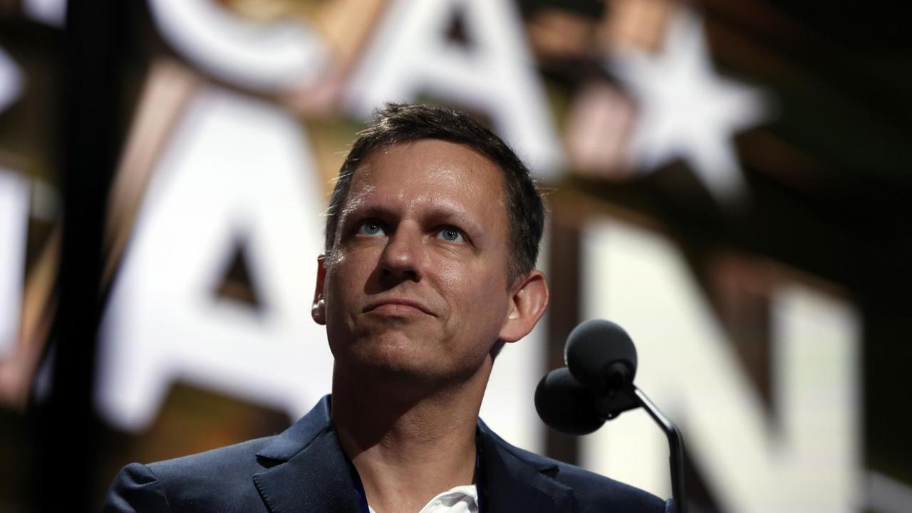Peter Thiel steht vor einem Mikrofon.