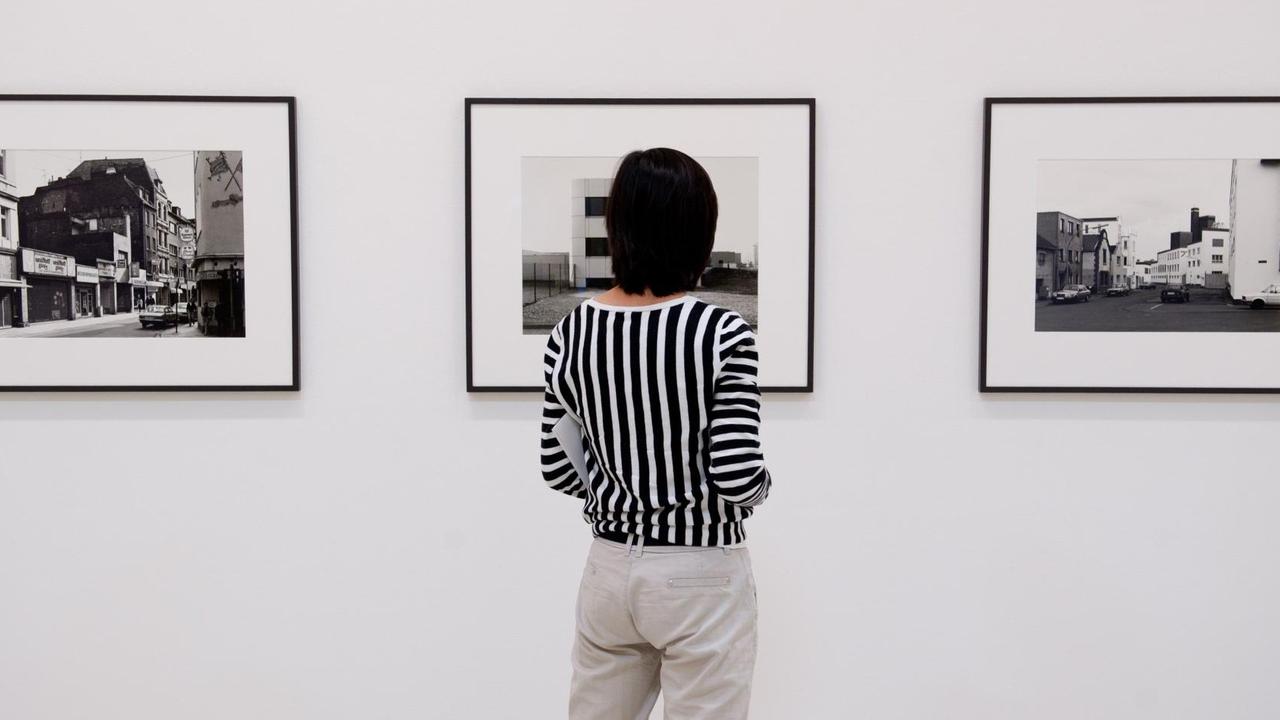 Eine Frau steht am 12.08.2013 in der Ausstellung «Wilhelm Schürmann. Bilder aus Deutschland» im Sprengel Museum in Hannover (Niedersachsen) vor den Fotografien "Eigelstein, 1989" (l-r), "Toyota, Köln, 1990" und "Köln, 1988" von Wilhelm Schürmann.