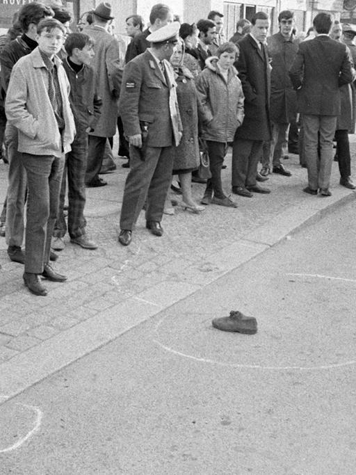 Passanten schauen auf die Schuhe von Rudi Dutschke, die noch am Tatort liegen. Dutschke wurde am 11. April 1968 vor der Geschäftsstelle des SDS am Kurfürstendamm niedergeschossen und lebensgefährlich verletzt.