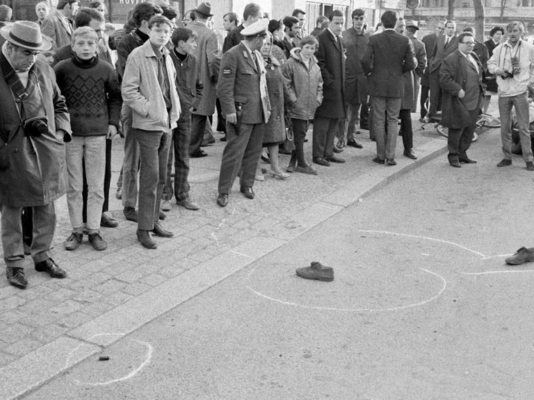 Passanten schauen auf die Schuhe von Rudi Dutschke, die noch am Tatort liegen. Dutschke wurde am 11. April 1968 vor der Geschäftsstelle des SDS am Kurfürstendamm niedergeschossen und lebensgefährlich verletzt.