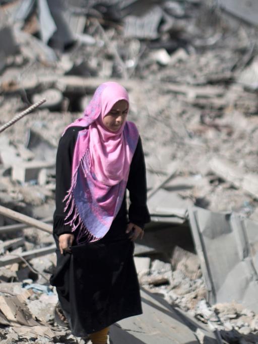 Eine palästinensische Frau läuft in Trümmern in Gaza Stadt umher.