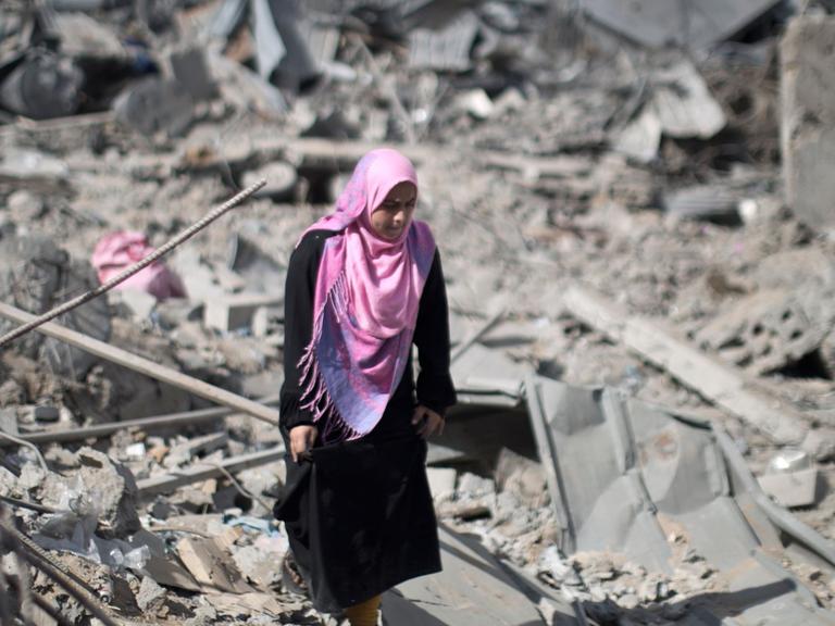 Eine palästinensische Frau läuft in Trümmern in Gaza Stadt umher.