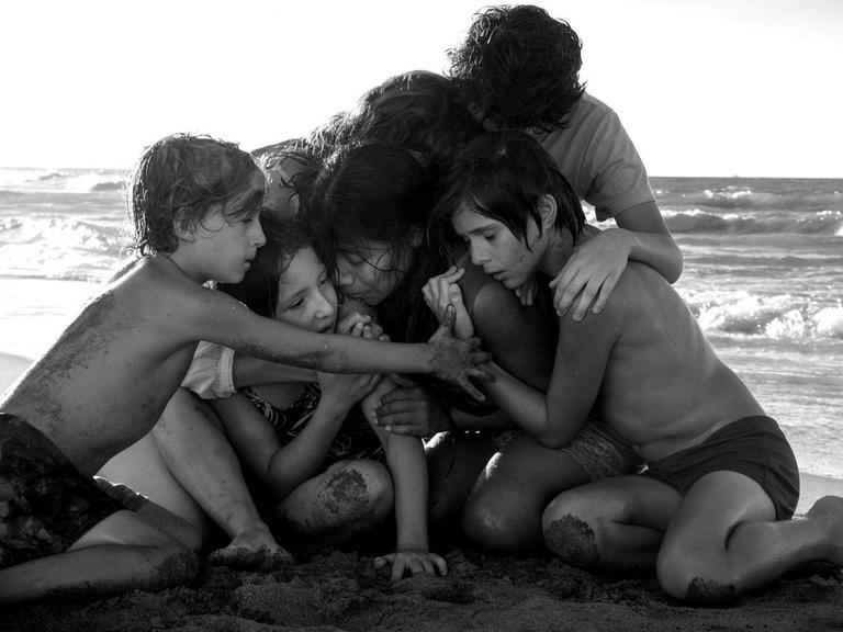 Filmszene aus Cuaróns "Roma": Die jugendlichen Hauptdarsteller kauern am Strand und umarmen sich.