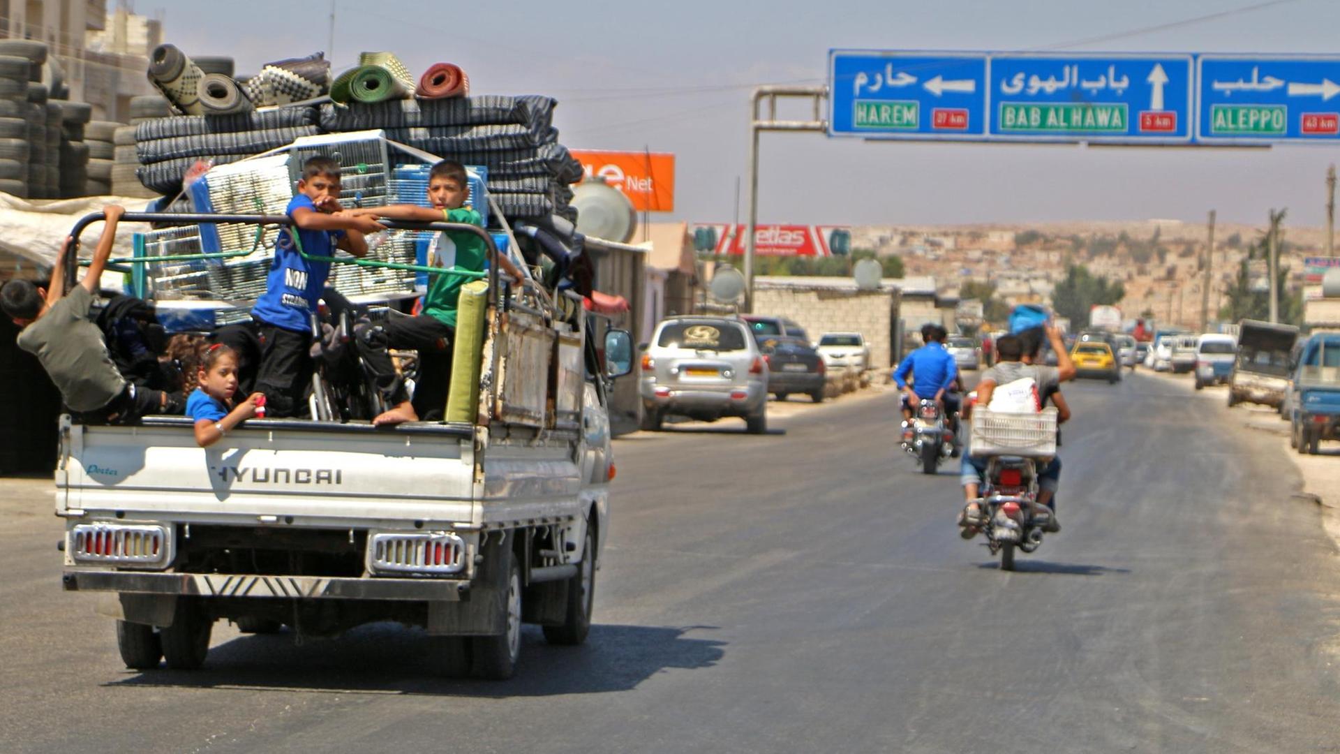 Auf einem Lastwagen hocken Kinder neben Gepäck, die Familie fährt aus Idlib in Richtung Norden.