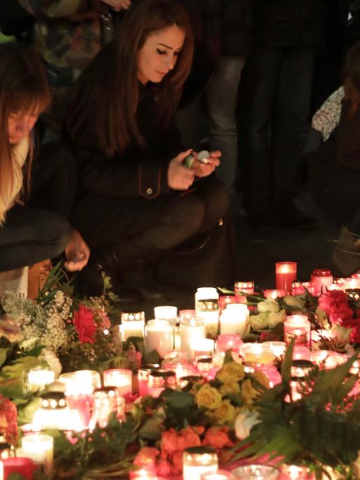 Passanten legen vor der Gedächtniskirche in Berlin zum Gedenken an die Opfer des Anschlags Kerzen und Blumen nieder.