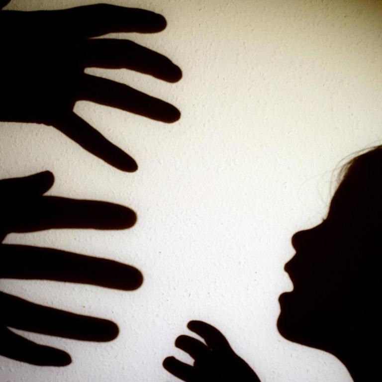 Das Bild zeigt Schattenrisse von drohenden Händen eines Erwachsenen und den Schatten eines Kinderkopfes.