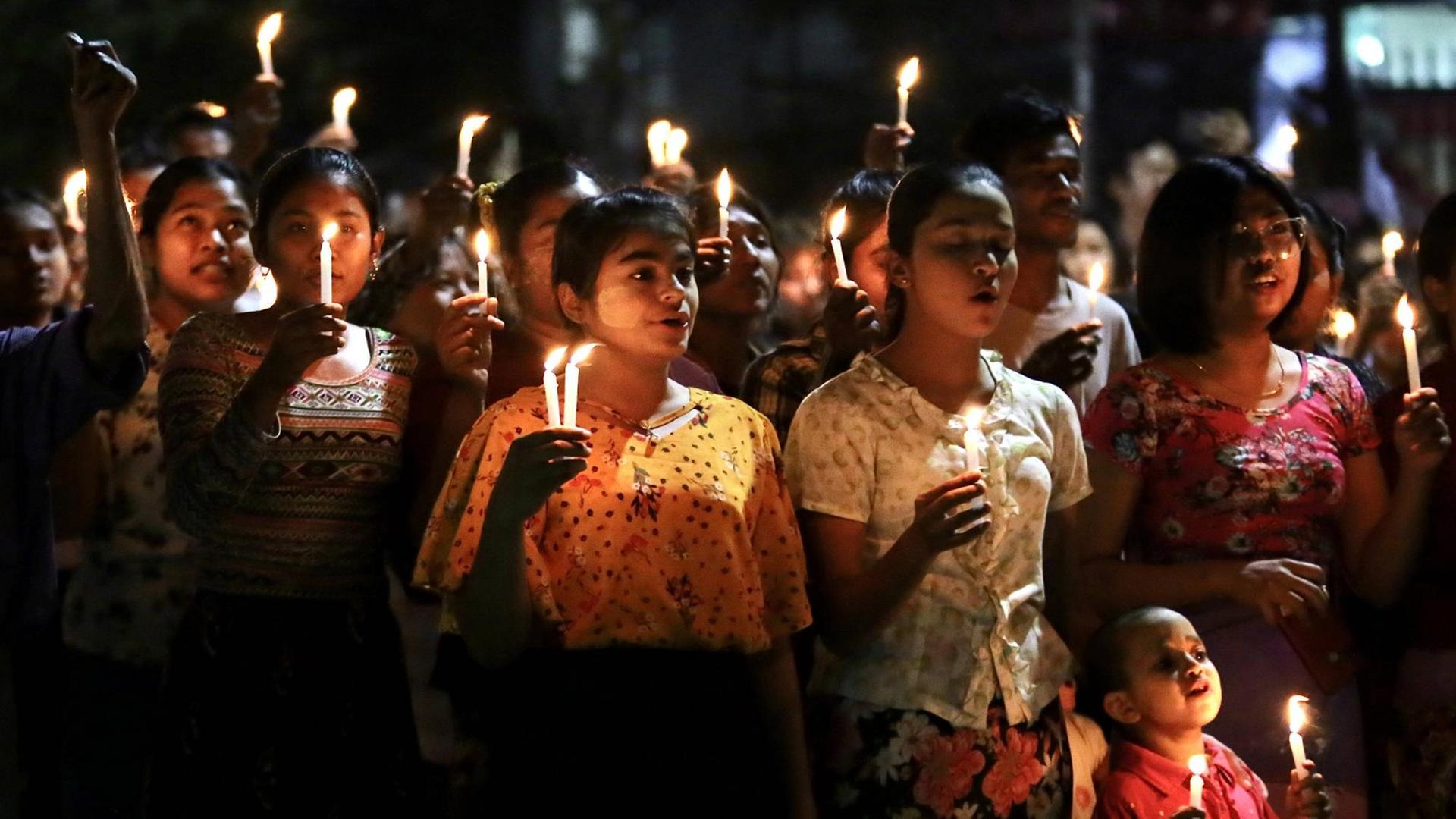 Auf dem Foto sind junge Menschen zu sehen, die im Rahmen der Proteste gegen die Militärregierung in Myanmar, nachts Kerzen hochhalten.