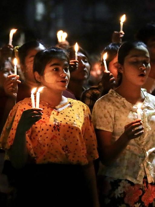 Auf dem Foto sind junge Menschen zu sehen, die im Rahmen der Proteste gegen die Militärregierung in Myanmar, nachts Kerzen hochhalten.