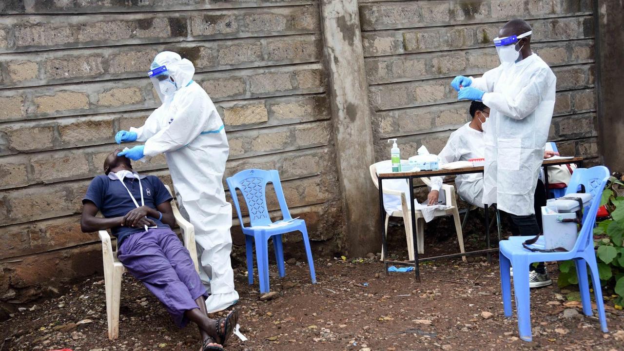 Medizinisches Personal führt auf einfachen Plastikstühlen und -Tischen Massentests auf COVID-19 im Slum von Kawangware in Nairobi durch