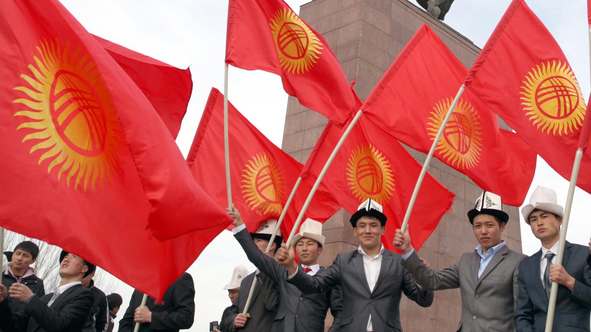Junge Menschen in Kirgistan halten halten kirgisische Flaggen
