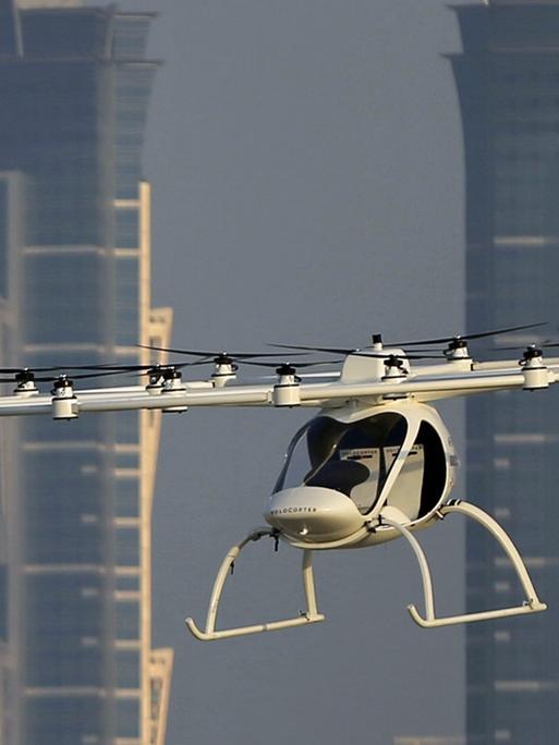 Ein Volocopter Prototyp fliegt am 26.9.2017 in Dubai, im Hintergrund zwei Wolkenkratzer.