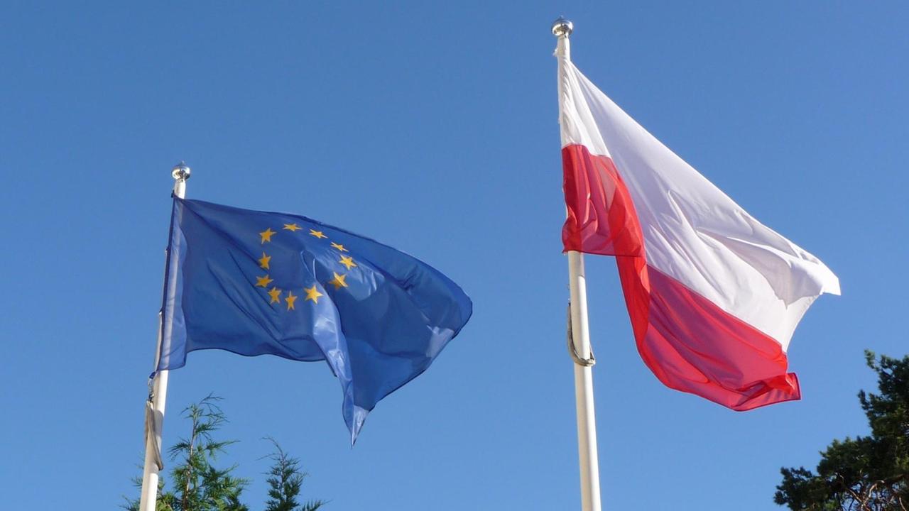 Eine polnische Flagge und eine Europafahne wehen im Wind.