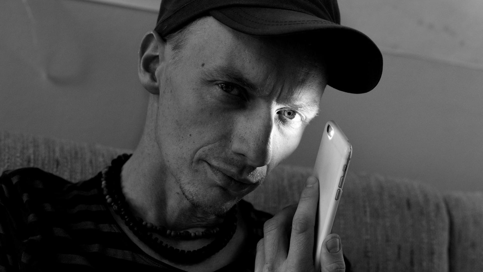 Der Filmregisseur Dietrich Brüggemann beleuchtet mit einem Smartphone-Lämpchen sein linkes Auge