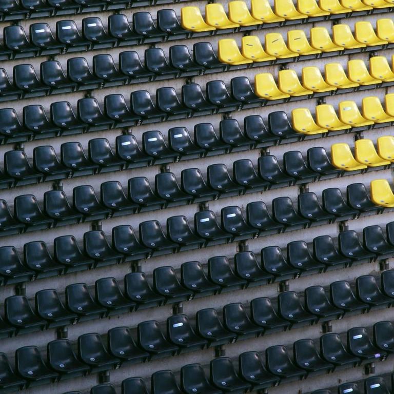 Ein Fan sitzt auf der leeren Tribüne im Dortmunder Fußballstadion.