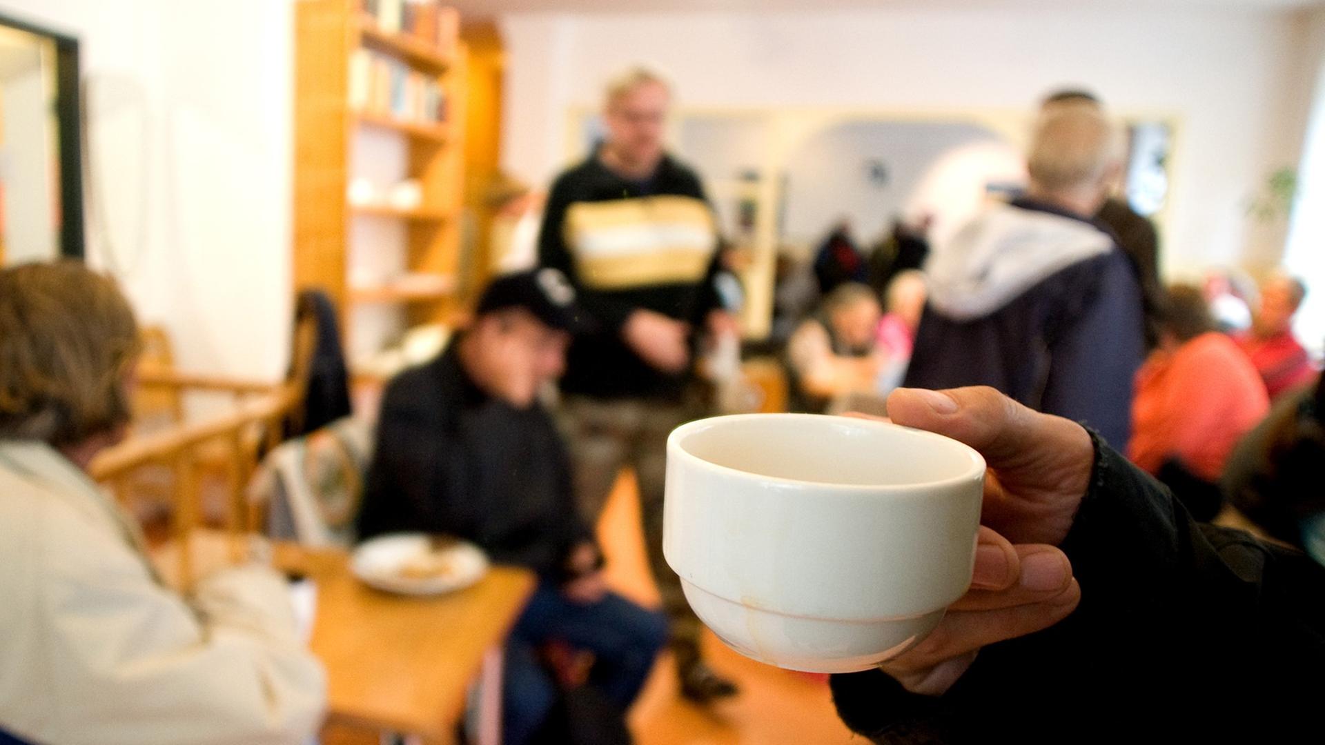 Bedürftige Menschen in der Wohnungslosen-Tagesstätte "Warmer Otto" der Berliner Stadtmission, im Vordergrund ist eine Tasse zu sehen.