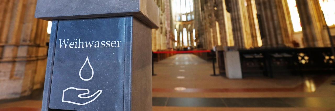 Nordrhein-Westfalen, Köln: Ein kontaktloser Weihwasserspender steht für die Gläubigen im Dom am Eingang bereit.