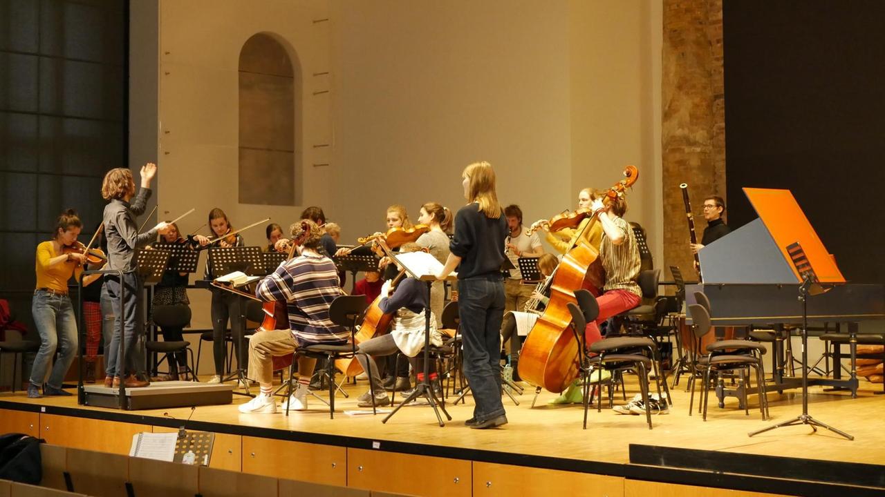 Orchester probt mit Solistin und Dirigenten auf der Bühne.