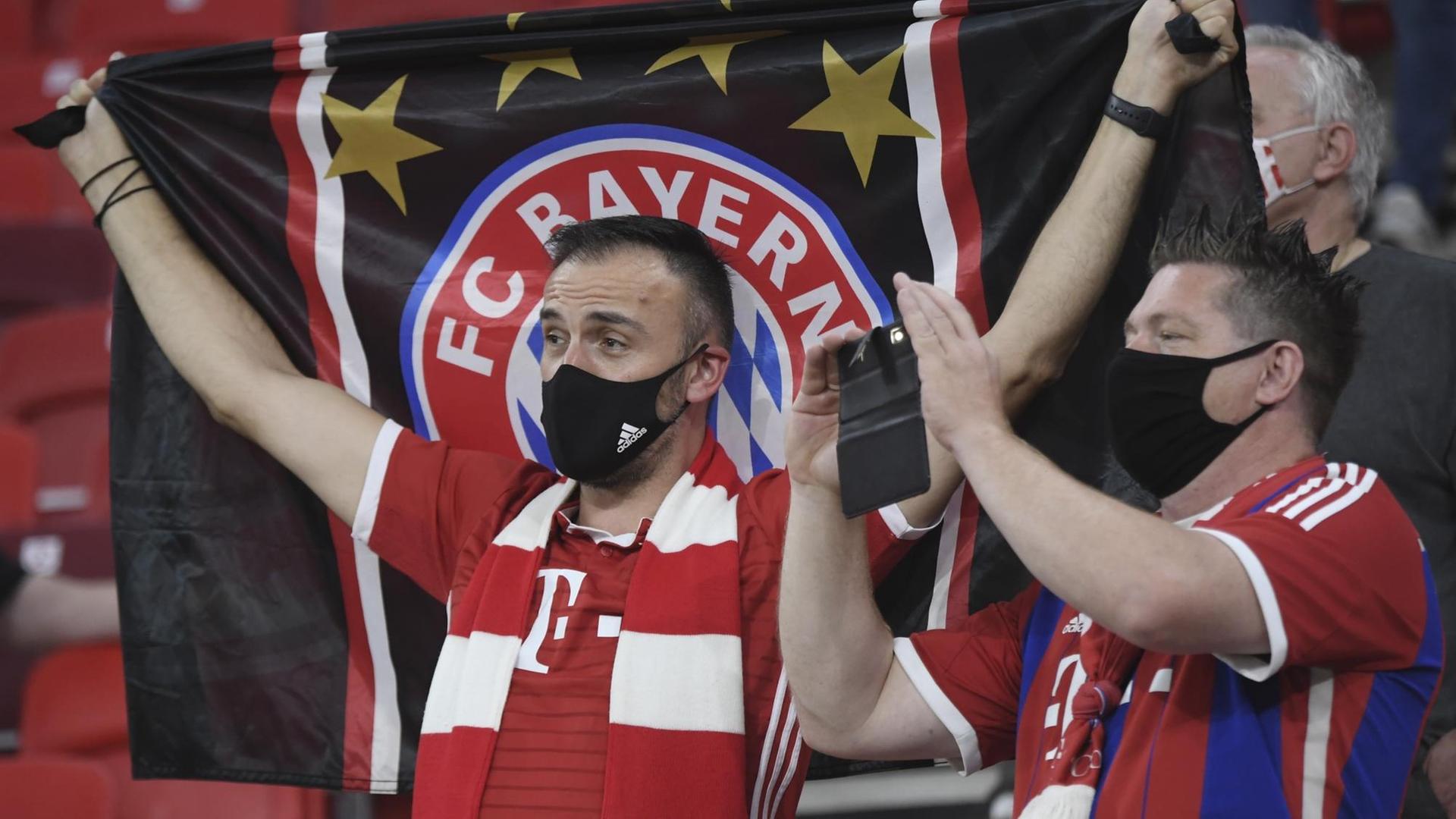 Fans von Bayern München stehen auf der Tribüne.