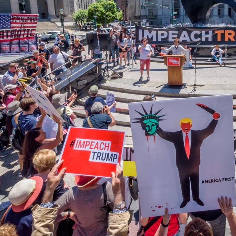 Demonstranten stehen mit Protestschildern rund um eine Rednerbühne am Foley Square in New York City.