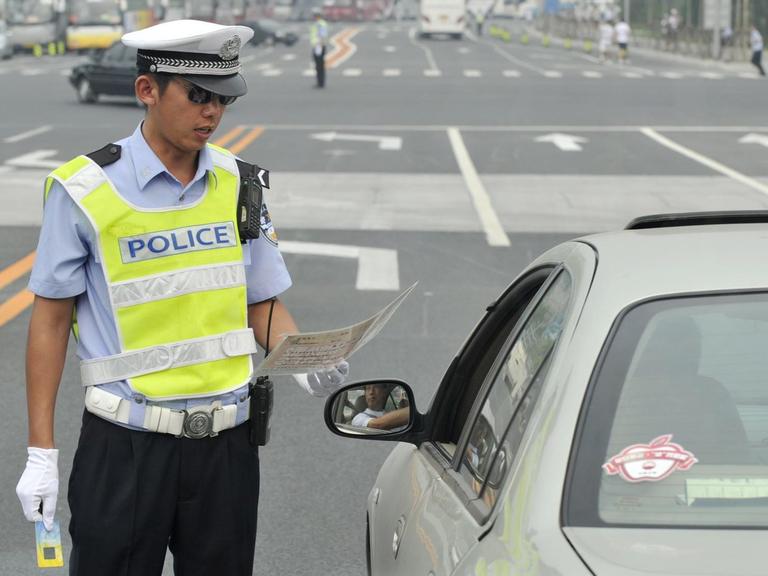 Ein chinesischer Polizist kontrolliert einen Autofahrer.
