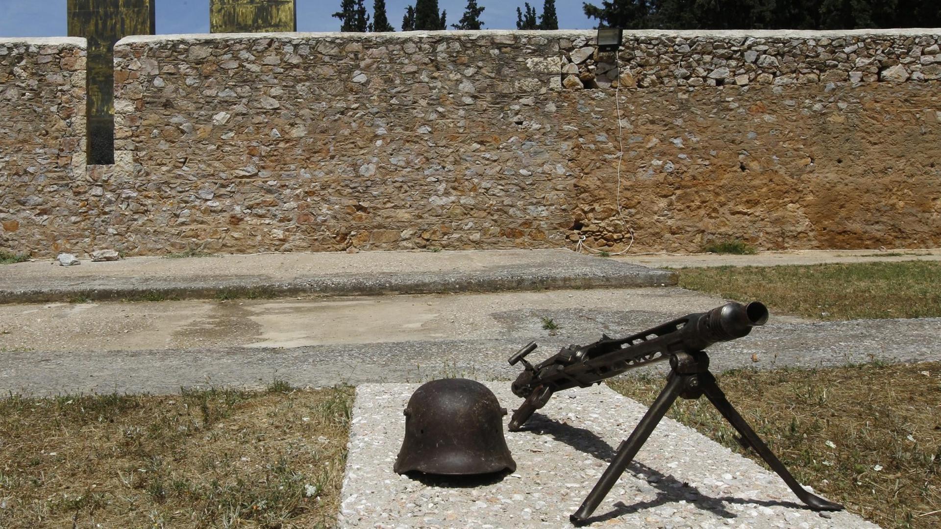 Ein Helm und ein Maschinengewehr aus der Zeit der deutschen Besatzung liegen an der Gedenkstätte im Park Skopeftirioin in Athen.
