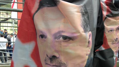 Erdogan-Befürworter vor der Lanxessarena in Köln halten eine Fahne mit Erdogan-Konterfei in die Kamera