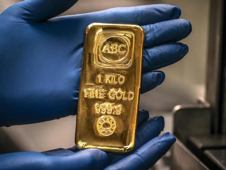 Ein Arbeiter hält einen Ein-Kilogramm-Goldbarren in den Händen.