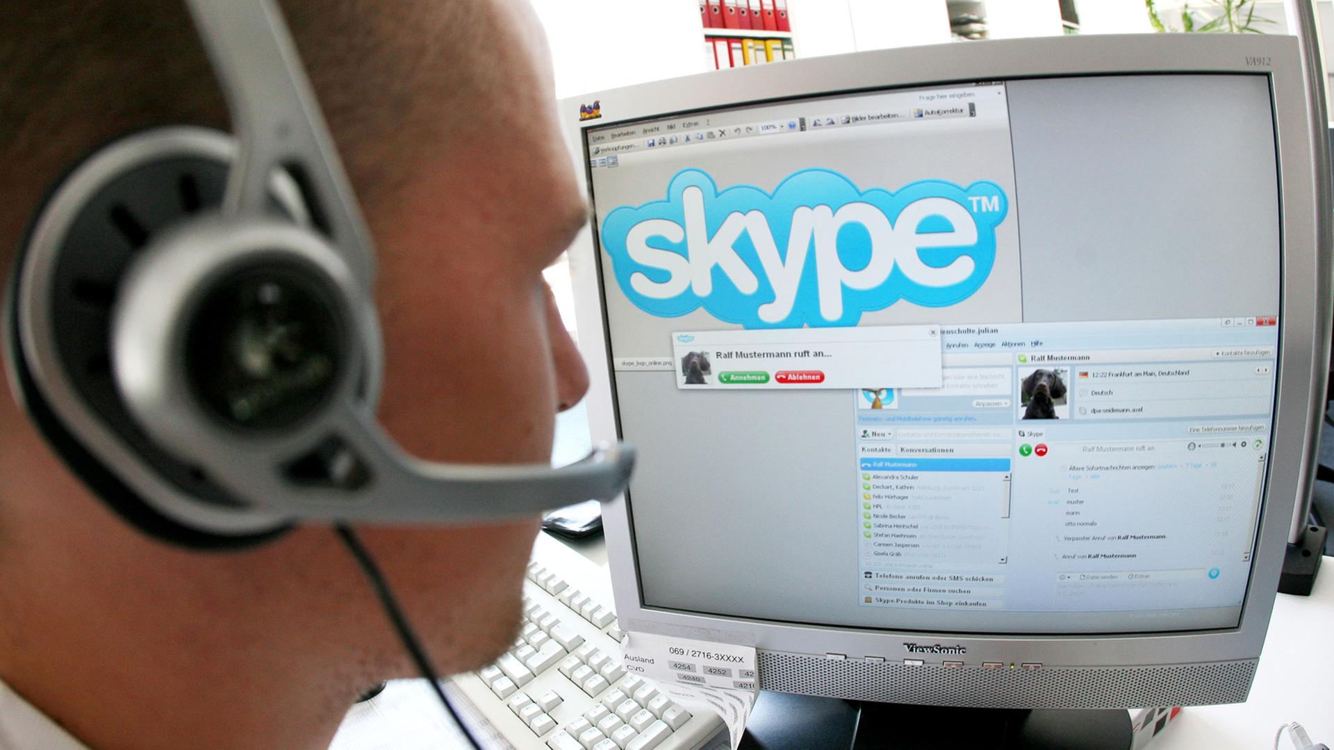 Ein junger Mann sitzt in Frankfurt am Main mit einem Headset vor einem Computerbildschirm und nutzt Skype, ein Programm, das unter anderem Internet-Telefonie ermöglicht.