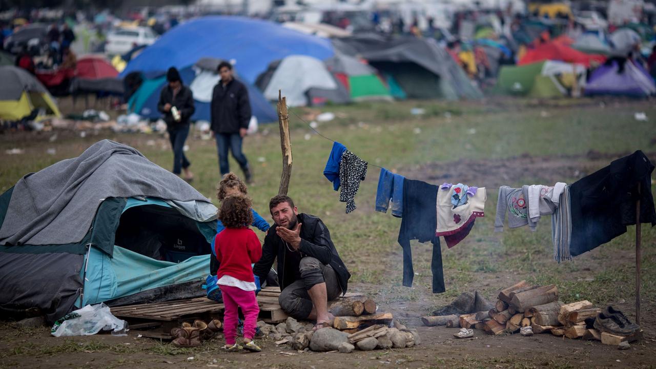 Ein Mann mit zwei Kindern sitzt am 11.03.2016 vor seinem Zelt im Flüchtlingslager in Idomeni an der Grenze zwischen Griechenland und Mazedonien. 