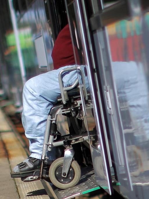 Ein Mann fährt in einem Rollstuhl aus einem Zug.