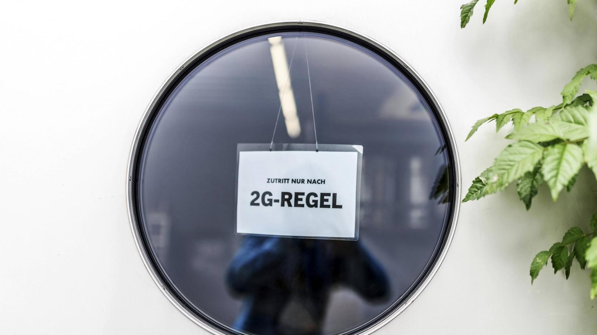 "Zutritt nur nach 2G-Regel" steht auf einem Schild im runden Fenster einer Tür. (Symbolfoto)