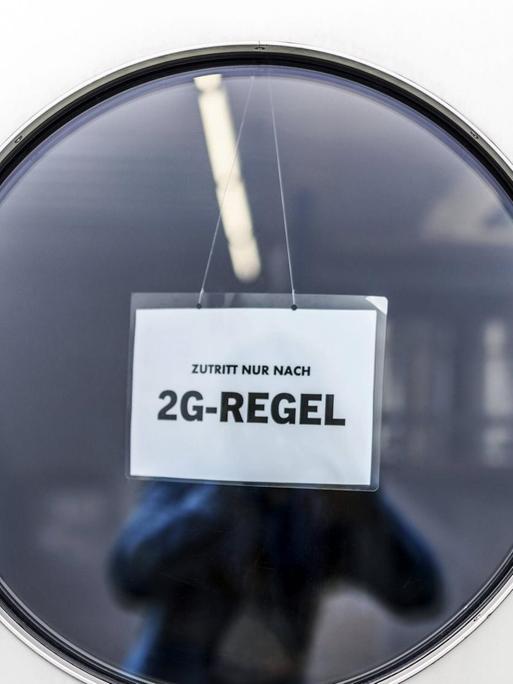 "Zutritt nur nach 2G-Regel" steht auf einem Schild im runden Fenster einer Tür. (Symbolfoto)
